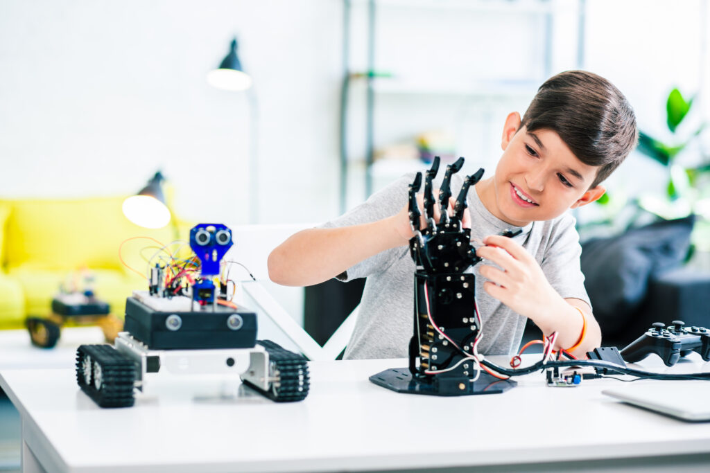 Joyful smart boy experimenting with robotic device